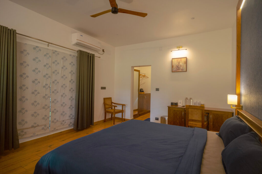 Twin bedded room in Mandaram villa at Giby Farm with a ceiling fan and soft lighting