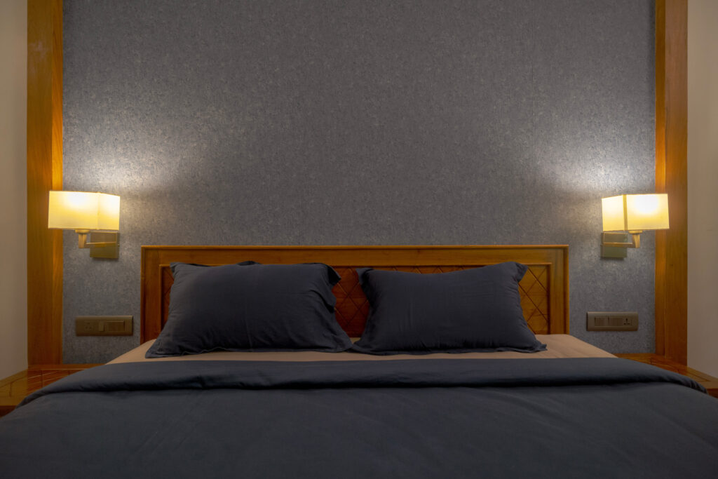 Master bedroom in Mandaram villa at Giby Farm with wall lamps and grey bedding