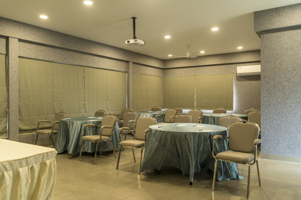 Indoor dining hall at Giby Farm set with round tables and cream drapes