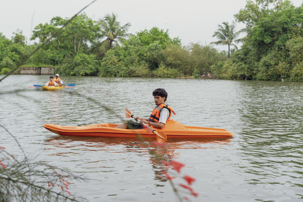 Guest paddling an orange kayak on the backwater at Giby Farm