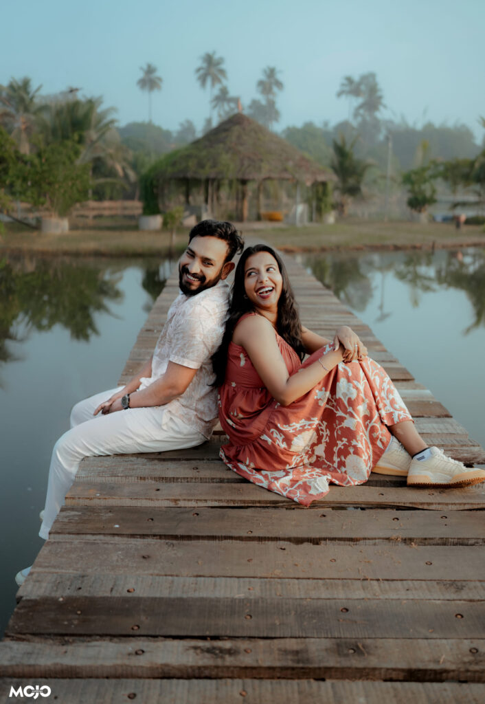 Couple seated on the jetty with the island huts behind them at Giby Farm