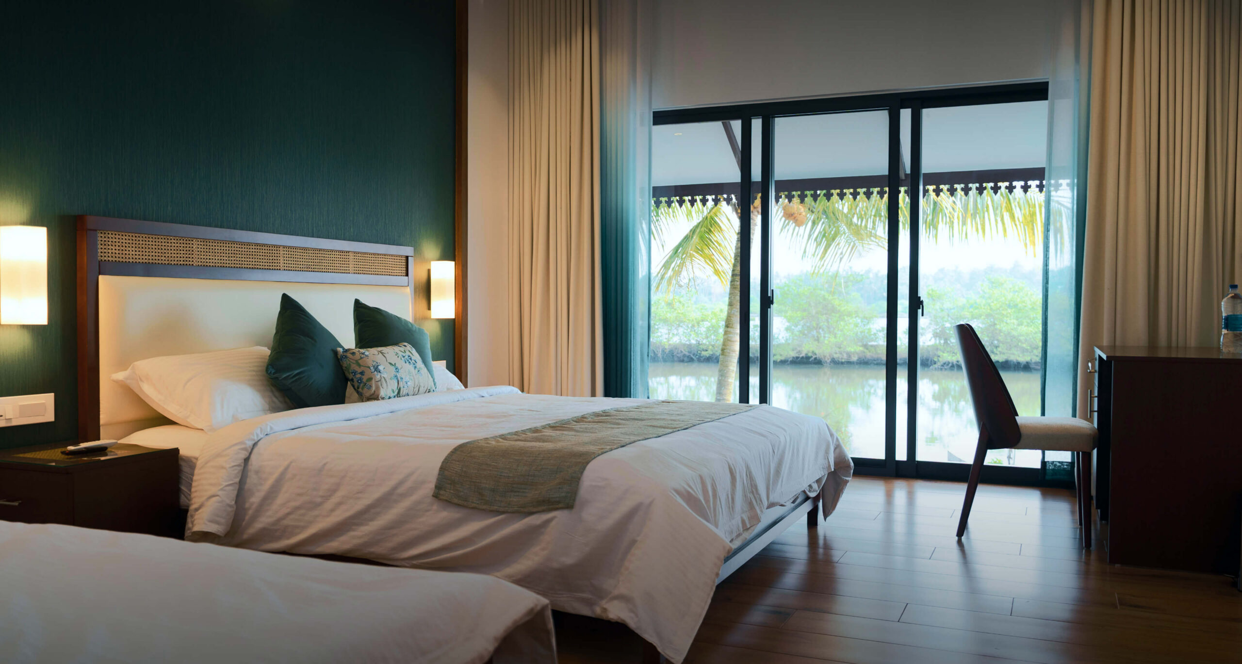 Twin-bed cottage bedroom at Giby Farm with a green feature wall and glass doors opening to the garden