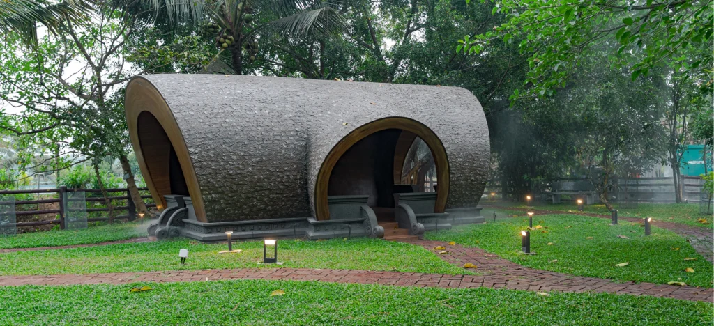 Curved dome cottage on the lawn beside the Nakshatra Vanam garden at Giby Farm