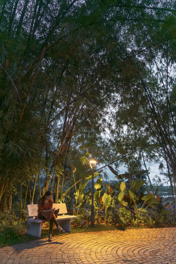 Guest sitting on a bench under the trees along a lantern lit path at Giby Farm