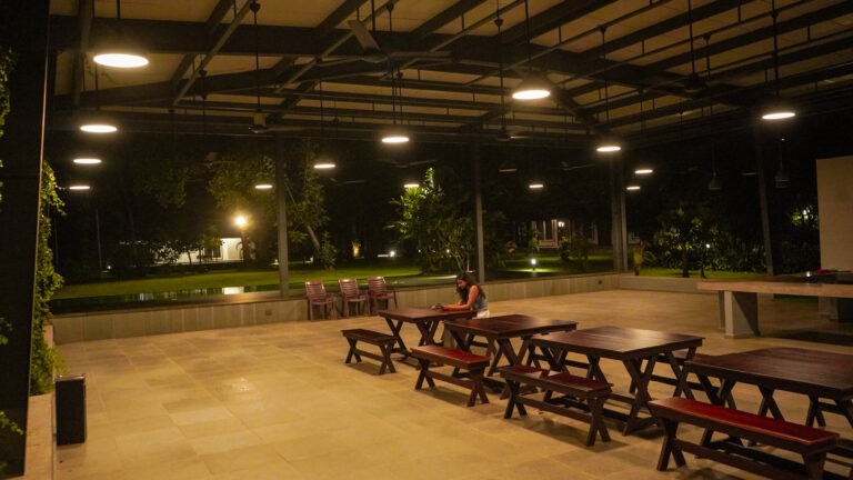 Event shed at Giby Farm lit up at night with long dining tables