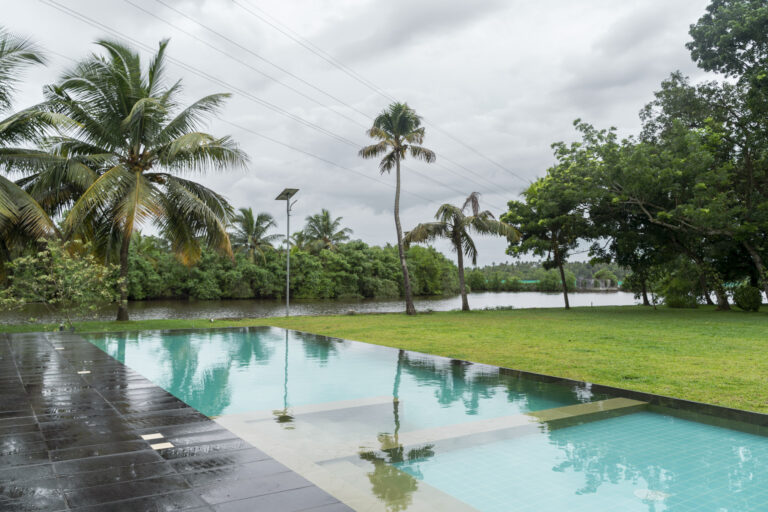 Swimming pool at Giby Farm surrounded by coconut palms beside the backwater