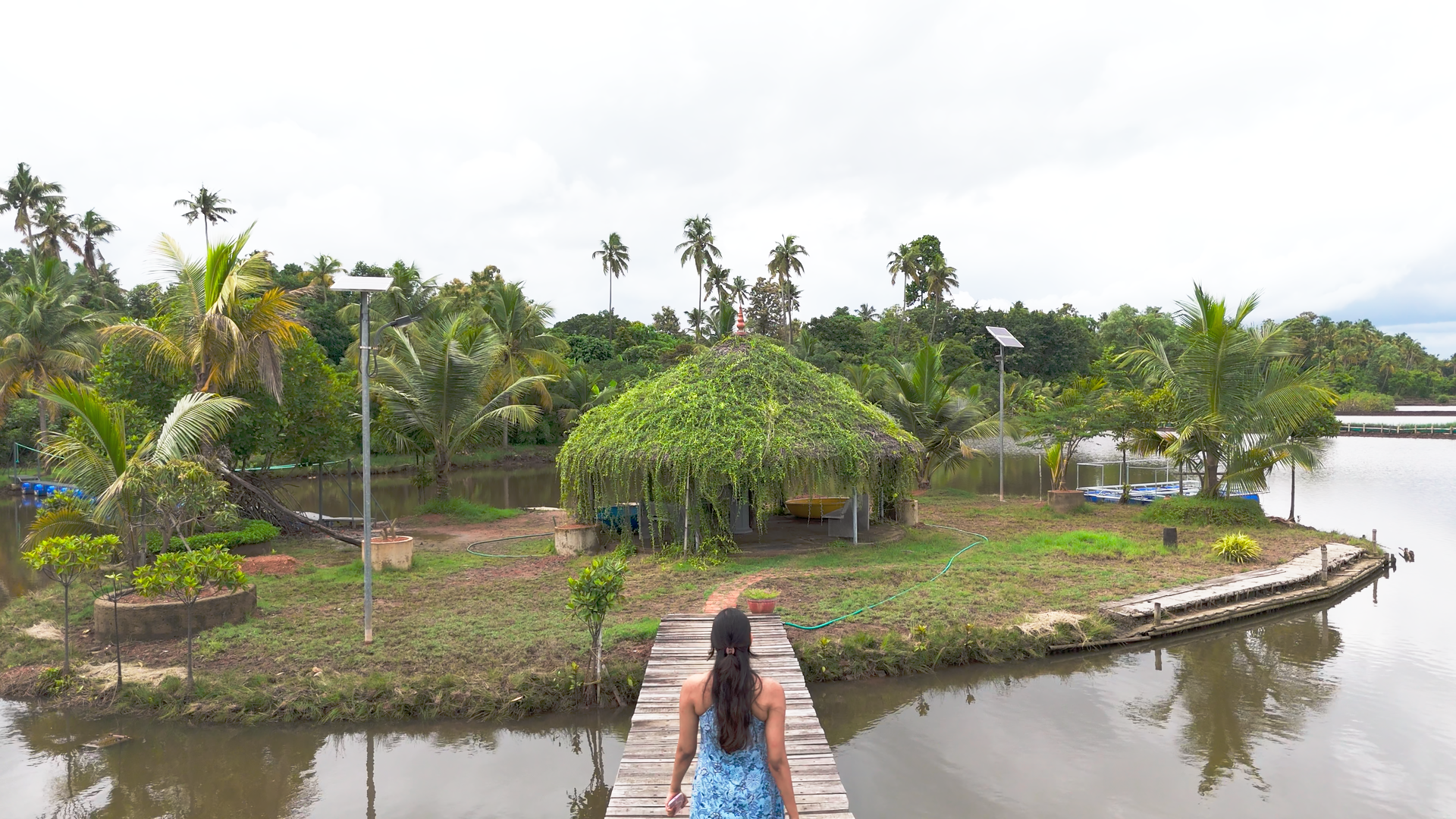 Thatched island huts linked by a walkway over the water at Giby Farm